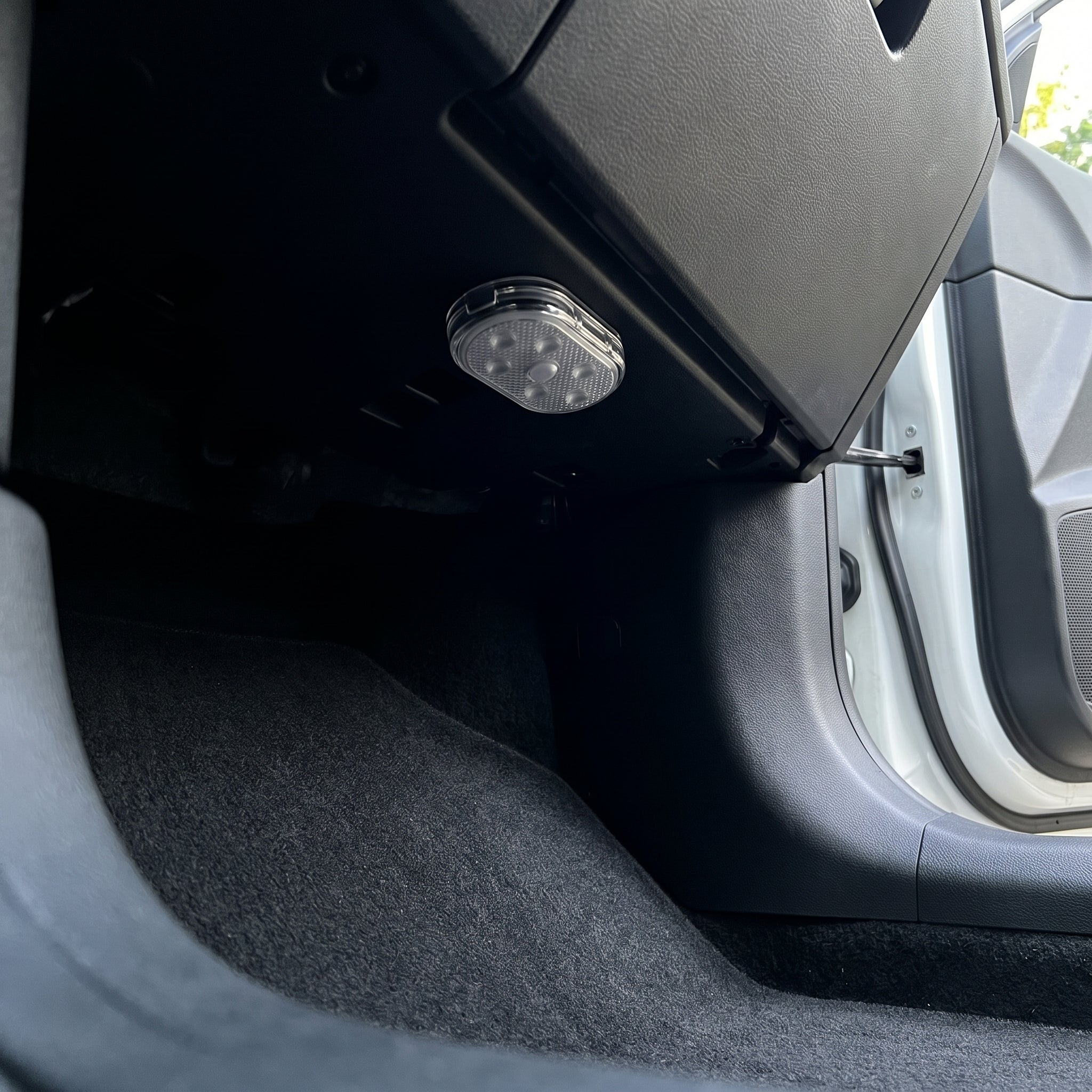 A Stealthglow light mounted deep under the dashboard, tucked back above the footwell of a clean car, switched off